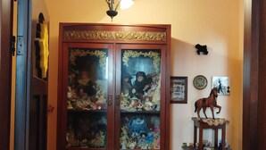 Ein traditioneller Holzkabinet mit Glastüren, ein kleiner Tisch mit einer Pferdefigure und ein an der Wand befestigtes Regal mit einer dekorativen Platte.
