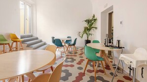 A modern meeting room with hexagonal patterned flooring, a variety of chairs, a round table, a potted plant, and a coffee machine. - IL GENIO Residenza d'Epoca (Pisa)