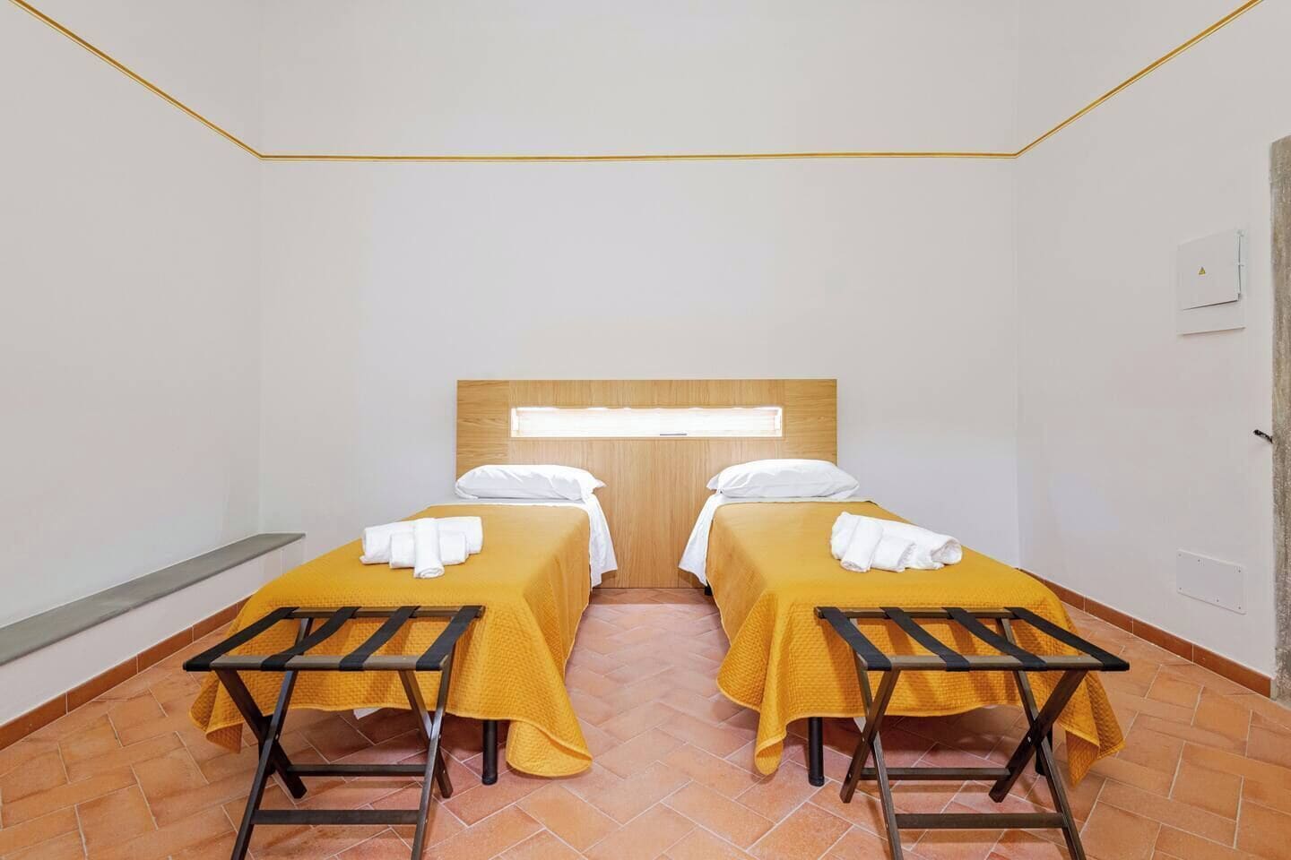 Ein Zimmer mit zwei Betten, jeweils mit gelber Bettdecke und weißen Kissen, sowie einem Holz-Kopfteil.