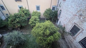 A courtyard with multiple trees and a stone building. - IL GENIO Residenza d'Epoca (Pisa)