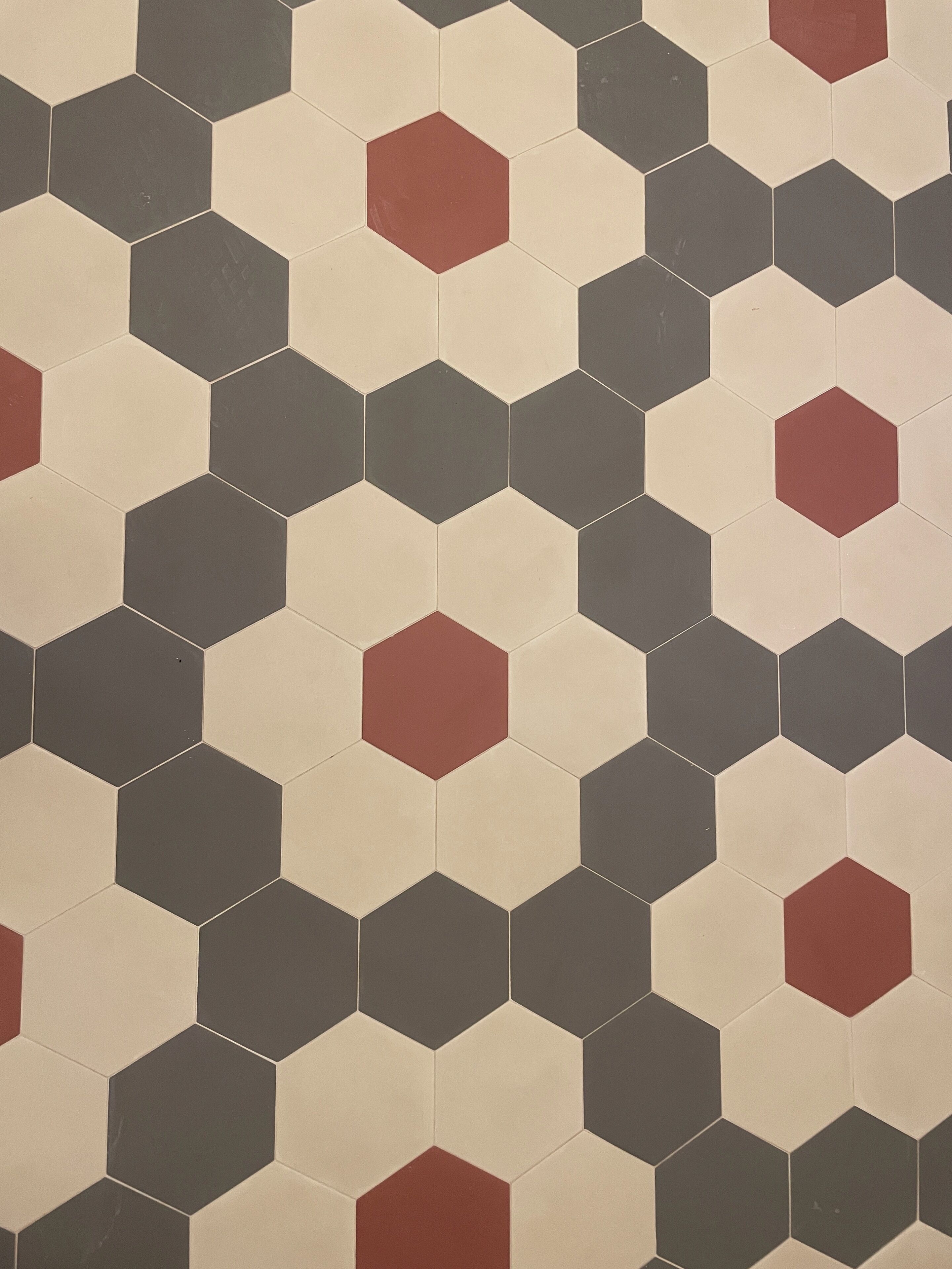A patterned floor with hexagonal tiles in shades of beige and gray, with occasional red accents.