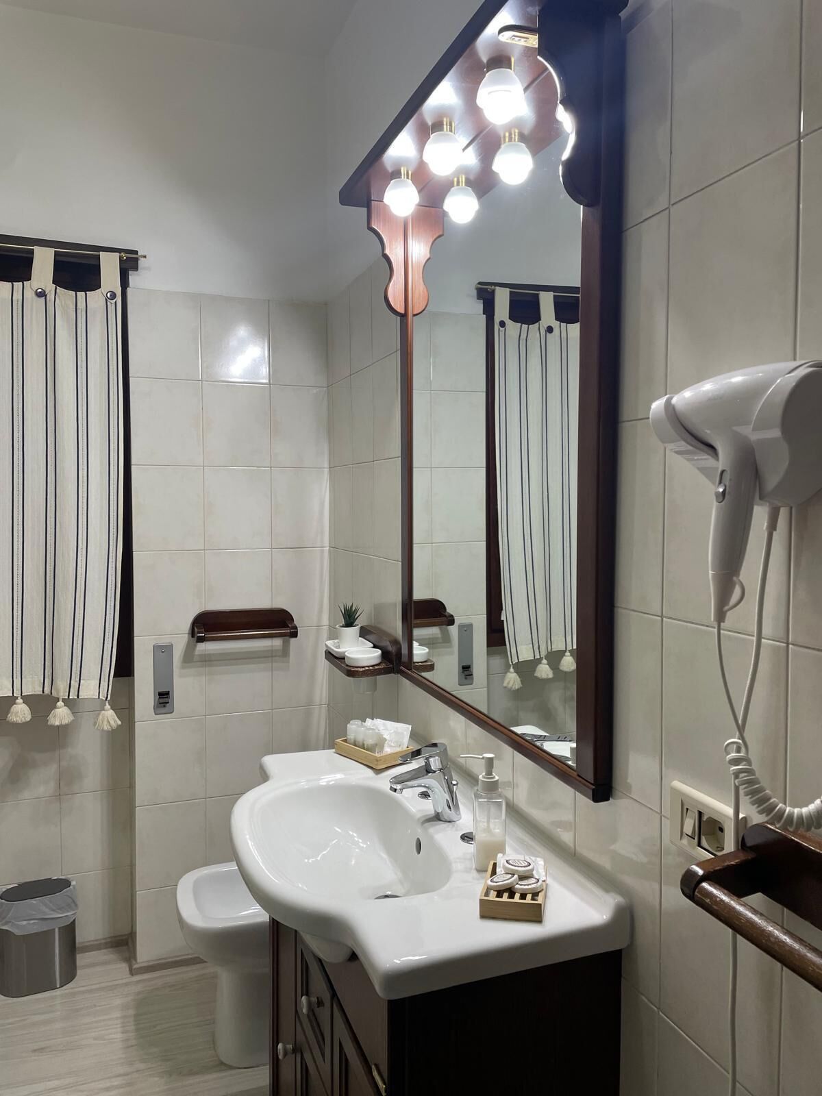 Un bagno moderno con uno specchio grande, un lavandino, un asciugacapelli e un portascopini.