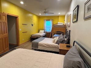 Ein Zimmer mit zwei Etagenbetten, einer Holztür, einem Deckenventilator und einem fenster mit Vorhängen.
