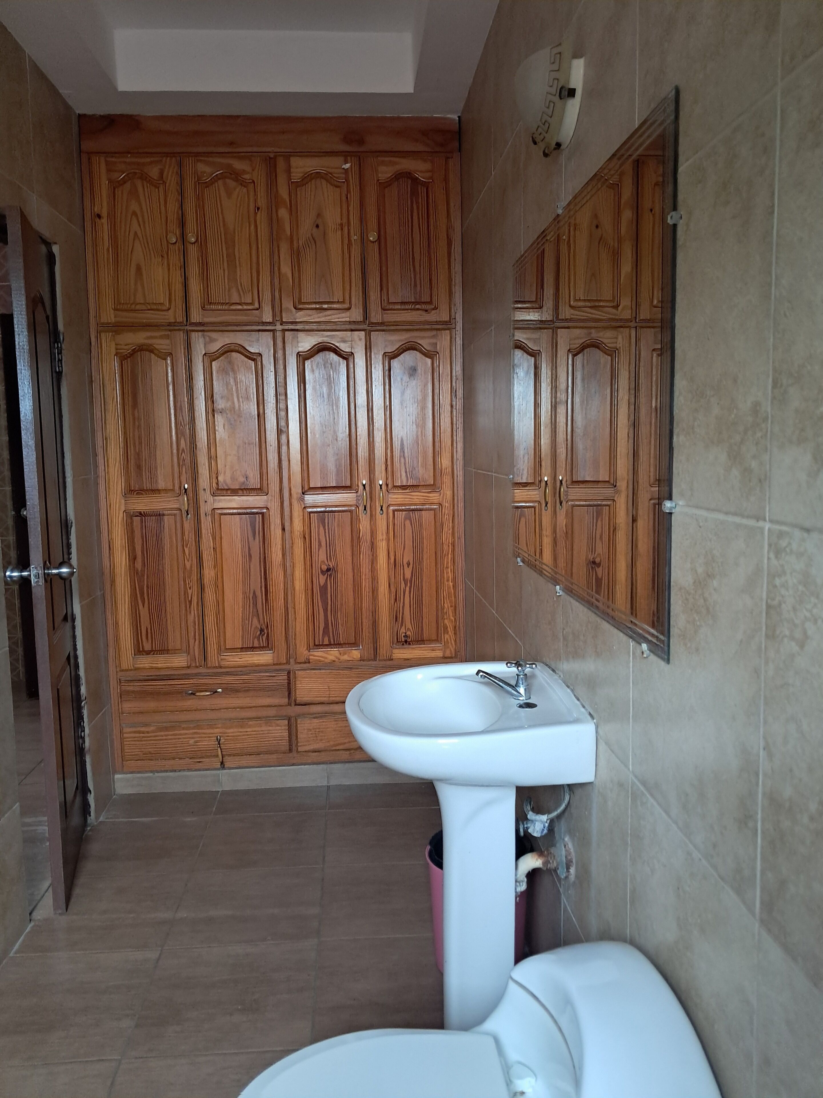 Ein Badezimmer mit Holzschränken, einem weißen Waschbecken und einer Toilette.