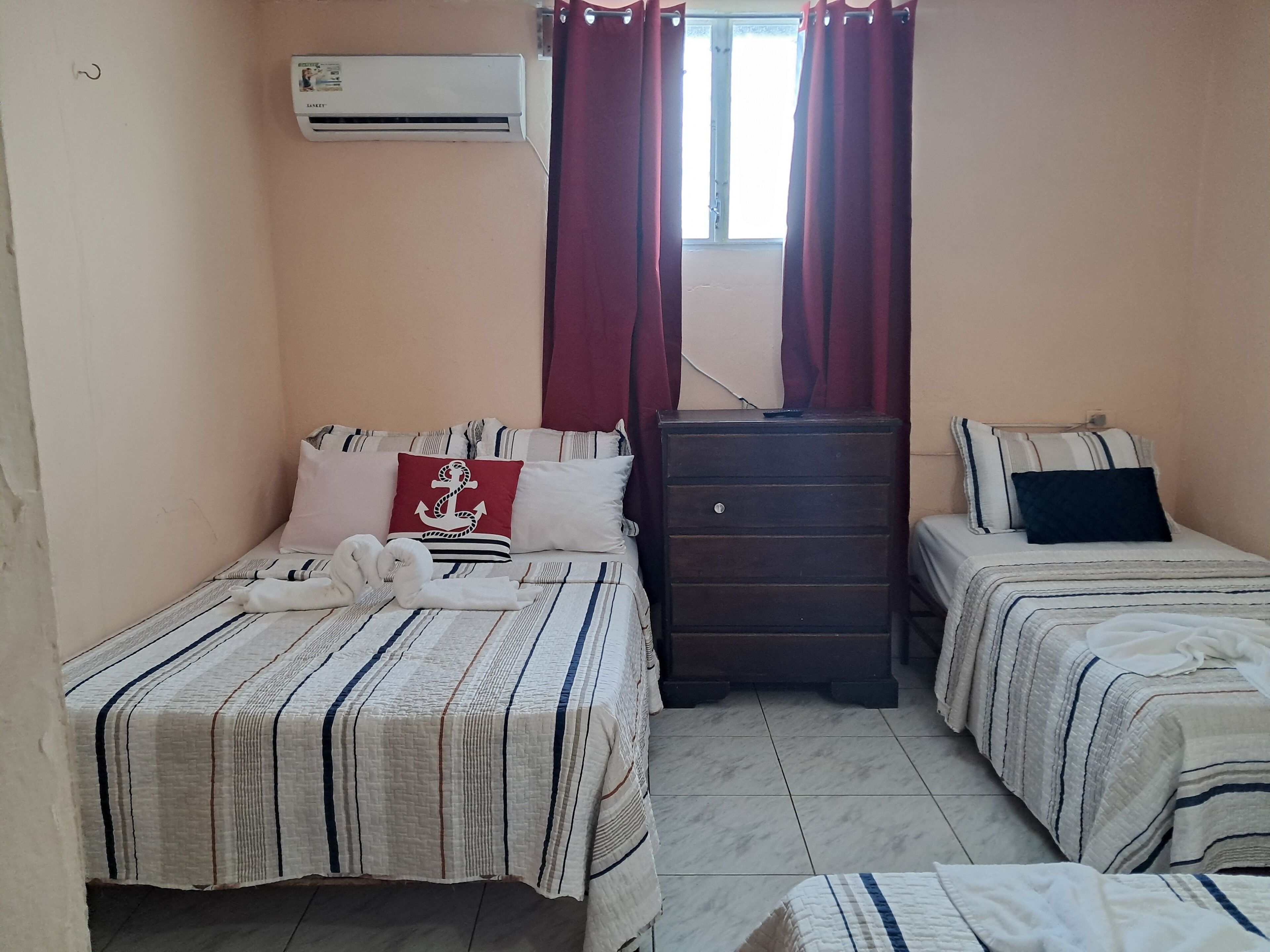 Un dormitorio con dos camas, un aparador y un equipo de aire acondicionado.