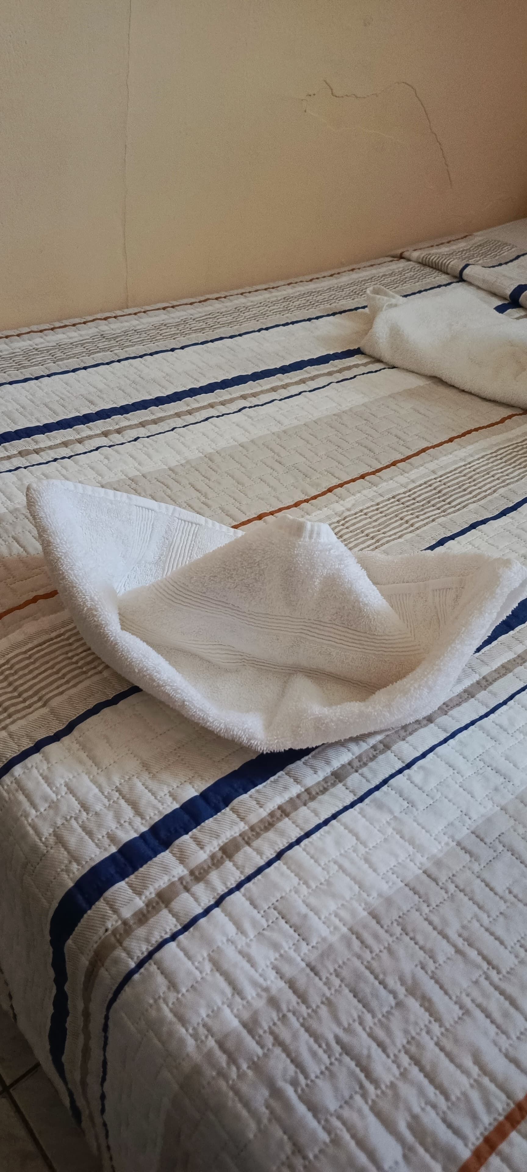 Un llit amb un edredó blanc amb ratlles blaves i marrons.