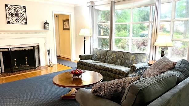 A living room with a fireplace, a sofa, a coffee table, and large windows.