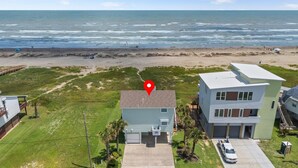 A two-story house with a garage, a driveway, and a view of the beach. - Relaxing Beachfront Escape (Galveston)