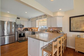 A modern kitchen with stainless steel appliances, white cabinetry, and a central island with bar stools.