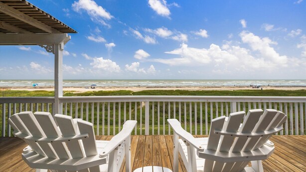 A wooden deck with two white Adirondack chairs facing a beach. - Relaxing Beachfront Escape (Galveston)