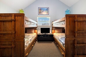 A room with two wooden bunk beds, a television, and a window with blinds.