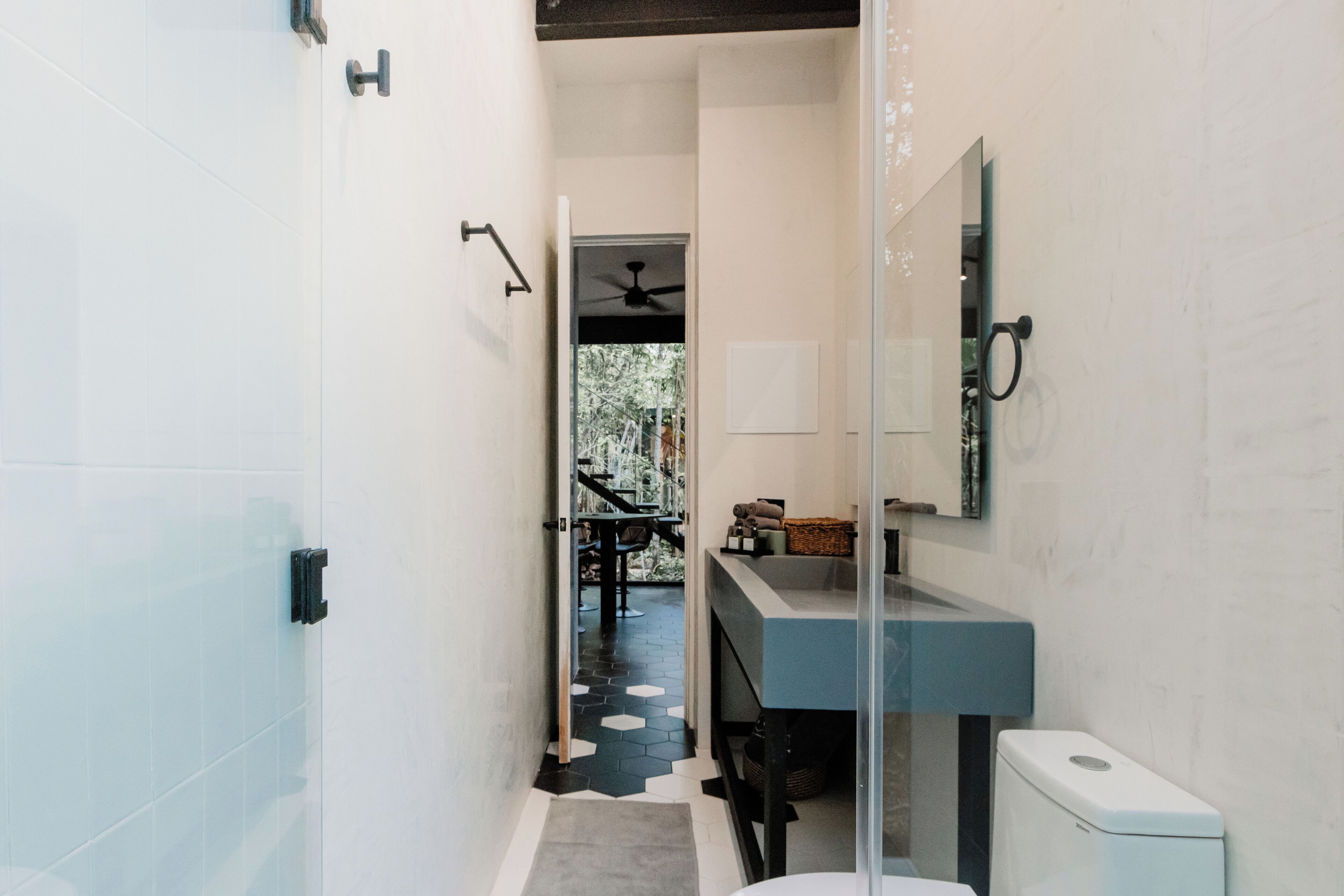 Ein modernes Badezimmer mit Duschkabine aus Glas, einem Waschbecken mit dunkler Arbeitsplatte und einer Toilette.