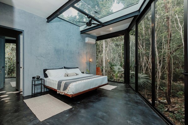 A modern bedroom with a large bed, a skylight, and a view of a forest. - SOTA Human Space Retreat Centre & Wellness Adults Only (Puerto Morelos)