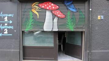 Un edificio de apartamentos con una persiana baja y un mural de hongos en la puerta.