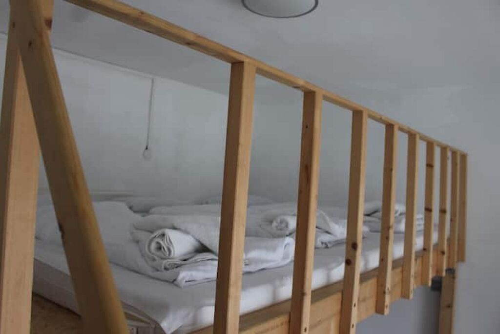 Een stapelbed met houten frames en witte beddengoed.