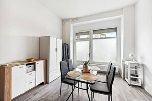 Una cocina moderna con una mesa de comedor, sillas y un armario.