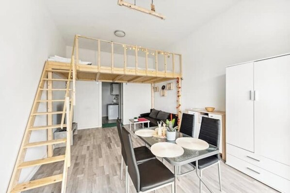 Una habitación compacta con literas, una mesa de comedor con sillas, un sofá y un armario.