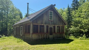 A wooden cabin with a gabled roof, surrounded by trees. - Charming cabin with AC in Burnham - Perfect getaway. (Burnham)