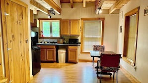 A kitchen with wooden cabinets, a dining table, and a red chair. - Charming cabin with AC in Burnham - Perfect getaway. (Burnham)