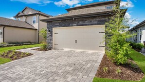 A residential house with a garage, paved driveway, and landscaped garden.