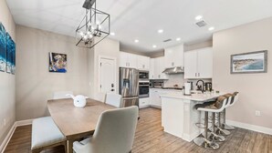 A modern kitchen with white cabinets, stainless steel appliances, and a bar area with stools.