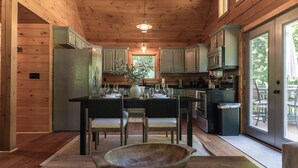 Une cuisine rustique, aménagée dans une cabane en bois, avec un îlot central, une table à manger et des chaises.