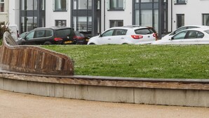 A modern residential building with multiple floors, large windows, and a parking area with cars. - Experience a sense of deep calm with seaside walks & blissful sea air (Portrush)