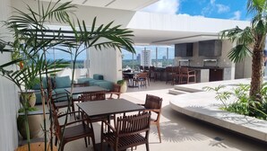 Una terraza moderna en la azotea con comedor, asientos y vistas del horizonte de la ciudad.