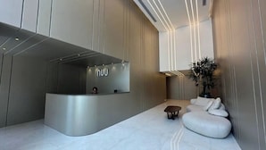 Una moderna zona de recepción con un mostrador curvo, una mesita y un área de estar con cojines.