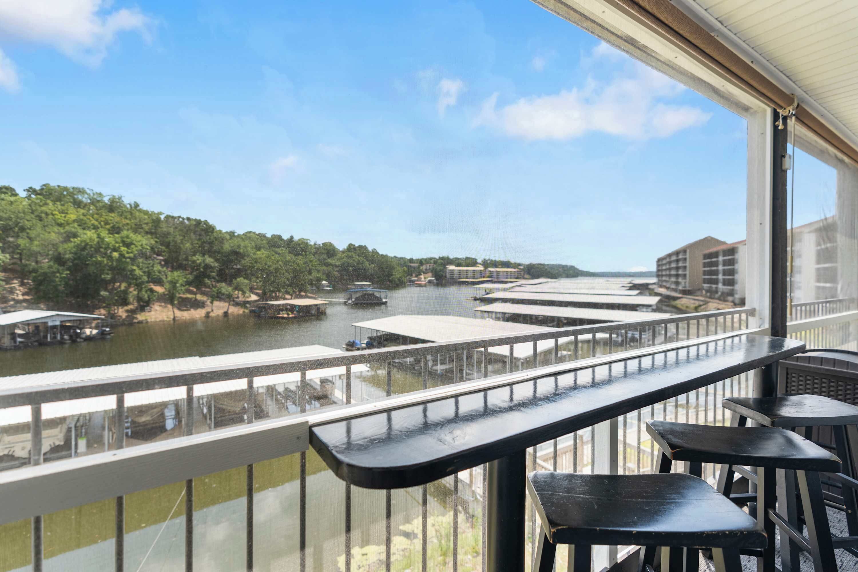 A balcony with a view of a river, boats, and buildings across the water.