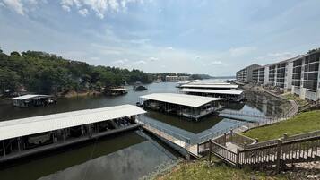 Un hôtel situé au bord de la rivière, avec plusieurs bateaux amarrés, un pont piétonnier et un bâtiment doté de grandes fenêtres.