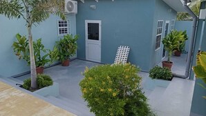 A blue building with a white door, potted plants, and a small garden area. - Casa Di Meche – Apartment (Sint Michiel)