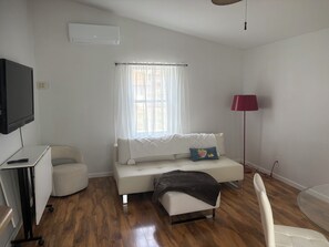 A modern living room with a sofa, a small table, a TV, and a window with curtains.