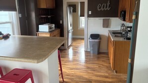 A kitchen with wooden cabinets, a stainless steel refrigerator, a microwave, and a trash bin. - 4-Bdrm 3 bath house in Grafton with large patio, WiFi and very walkable. Fun!!! (Grafton)