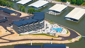 Un hotel de varios pisos con piscina en la azotea y un puerto deportivo con barcos.