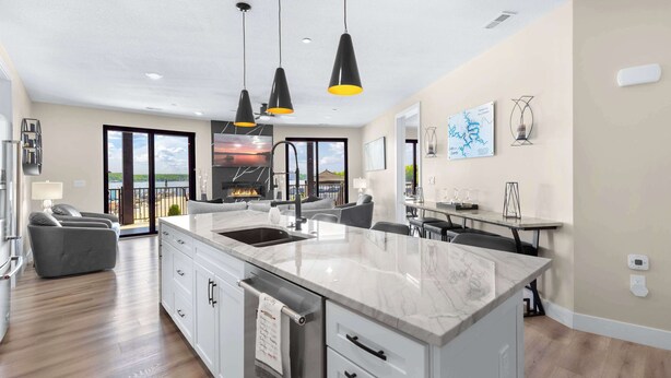 Una cocina moderna con una isla grande, lámparas colgantes negras y vistas al exterior.