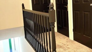 Eine Treppe mit einer schwarzen Geländer und einer Tür im Hintergrund.