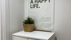 Un cartel con texto motivacional en una pared, una planta en maceta y un armario blanco con dos puertas.