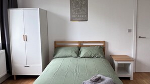 Un dormitorio con cama, armario, mesita de noche y un cartel en la pared.