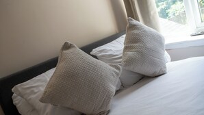 Un lit avec du linge de lit blanc et deux oreillers à texture particulière.