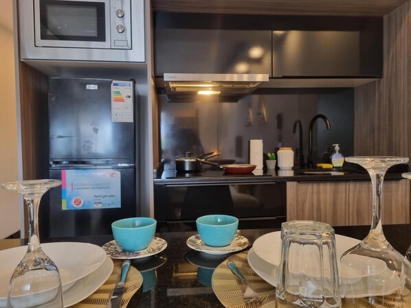 A modern kitchen with a refrigerator, stove, and sink. There are blue bowls and plates on the counter.