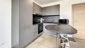A modern kitchen with grey cabinets, a black countertop, and a built-in oven.