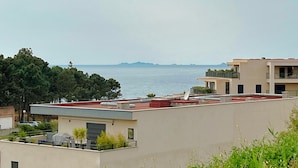 A residential building with a flat roof, a satellite dish, and a view of the sea.
