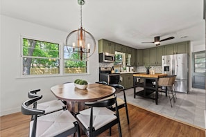 A modern kitchen with a dining area, large windows, and a ceiling fan. - Entertainment Haven! Firepit, Game Room, and Large fenced-in yard (Janesville)