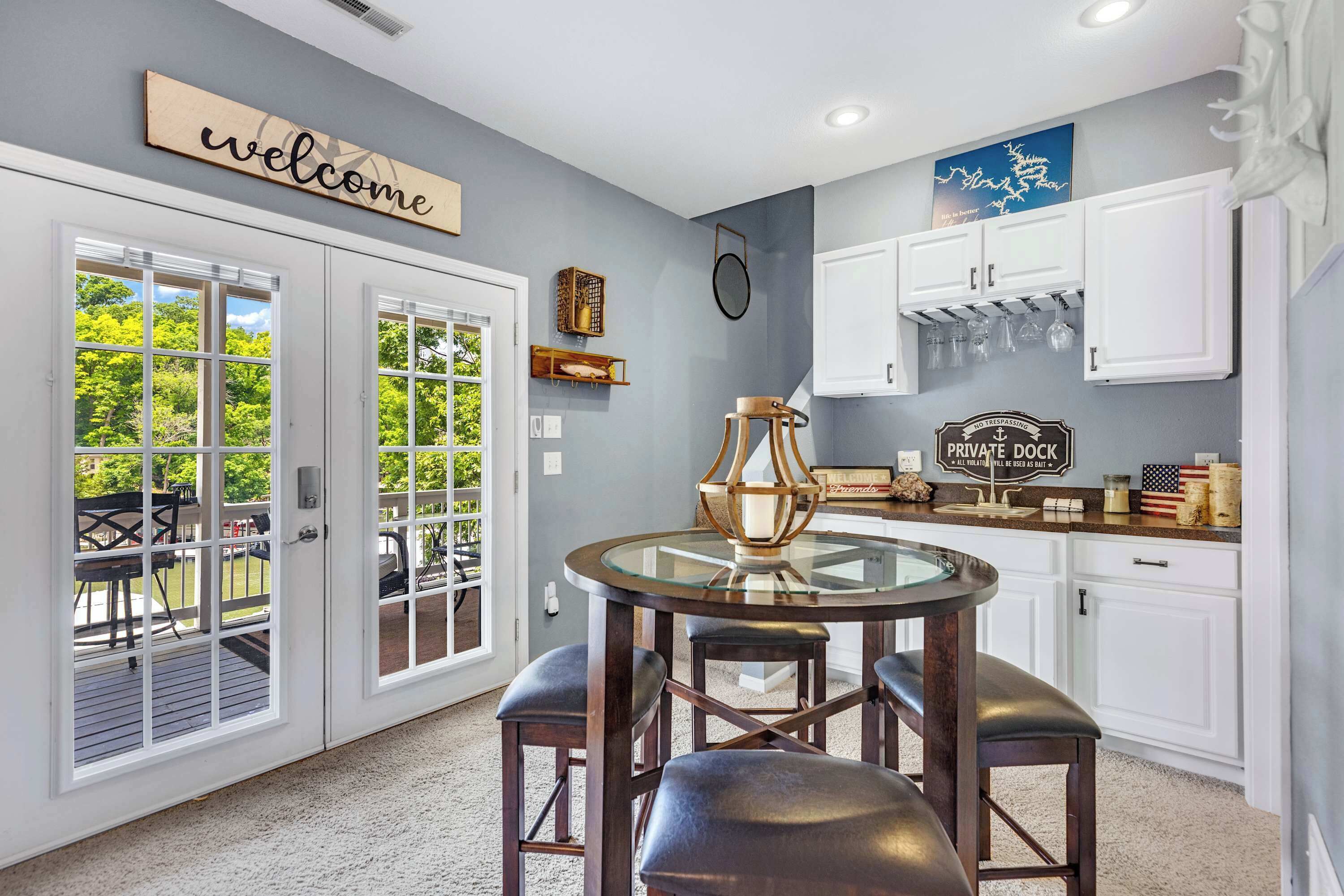 A kitchen with white cabinets, a round glass table, and a 'Welcome' sign.