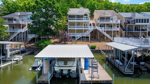 A waterfront property with multiple buildings, a dock with boats, and a covered boat launch area. - Shore Thing - Lakefront for 12 (Lake Ozark)