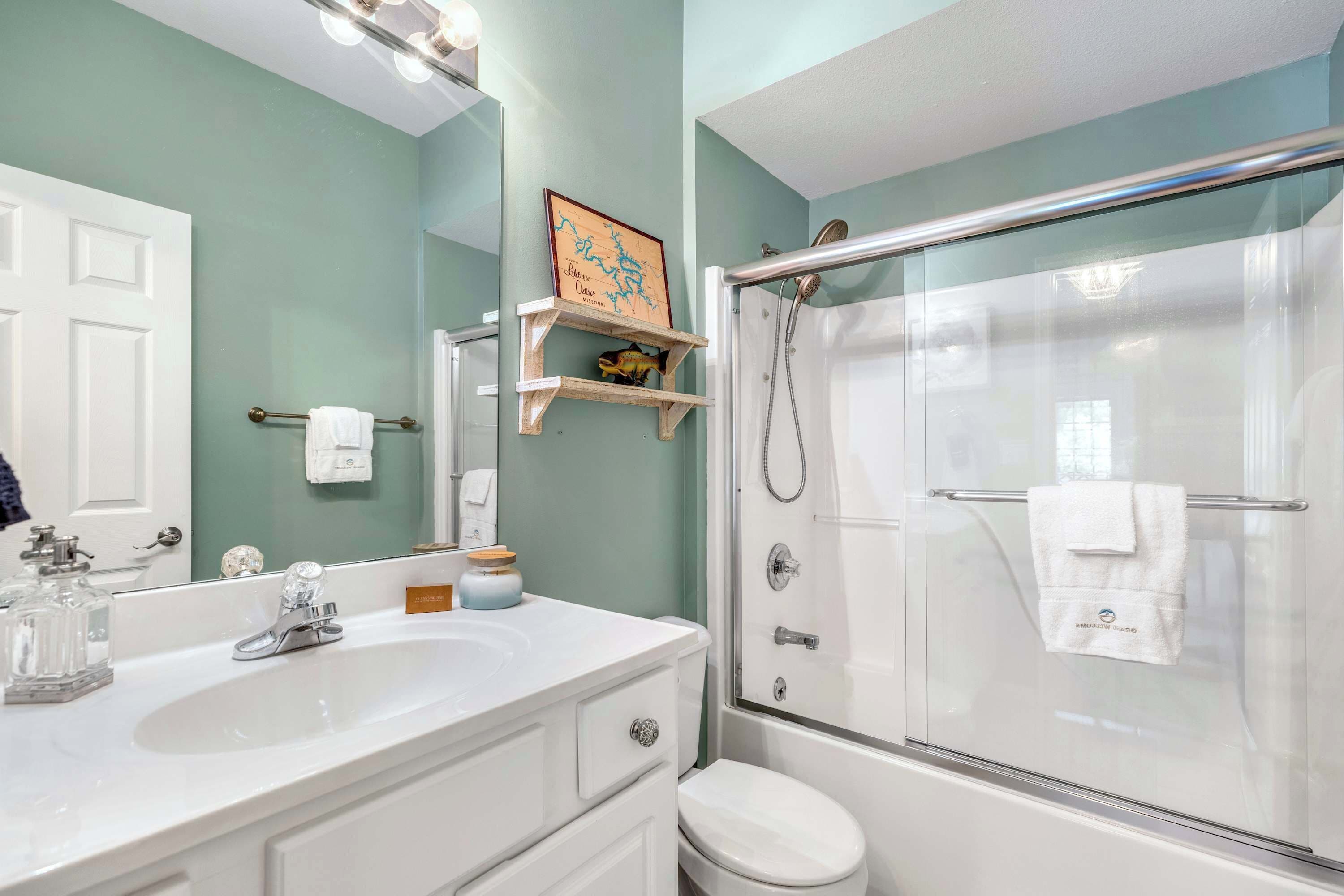 A bathroom with a white sink, mirror, and glass shower enclosure.