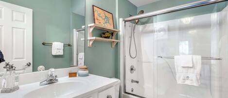 A bathroom with a white sink, mirror, and glass shower enclosure.