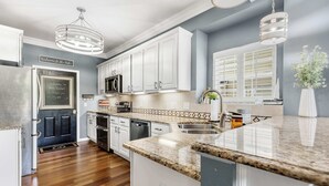 A modern kitchen with white cabinets, granite countertops, and a central island. - Shore Thing - Lakefront for 12 (Lake Ozark)