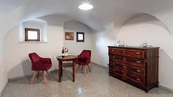 Una habitación con una mesa de comedor, dos sillas, un aparador y un ventanal pequeño.